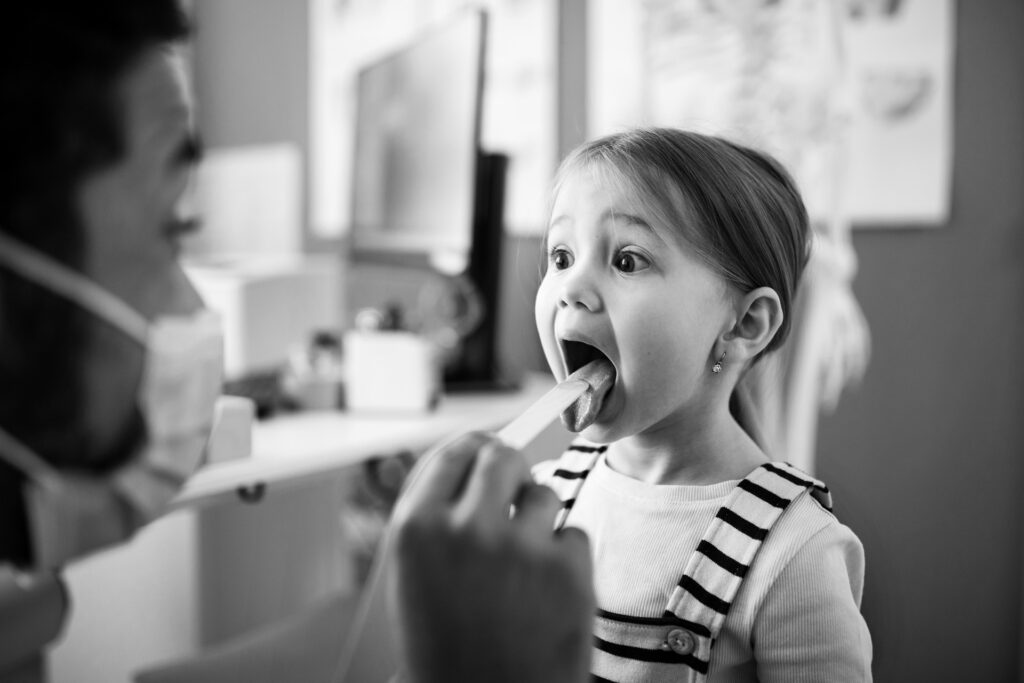 Ein Arzt der MyPermanence blickt in den Rachen eines Kindes.